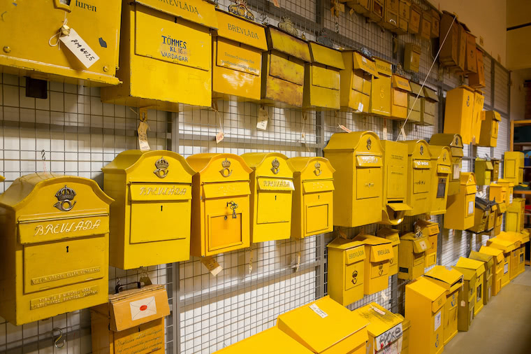 A wall filled with yellow Swedish mailboxes