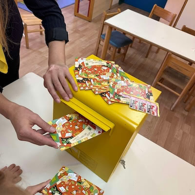 School children posting postcards on a yellow mailbox